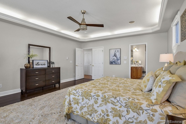 bedroom featuring dark wood-type flooring, a raised ceiling, ceiling fan, connected bathroom, and a closet