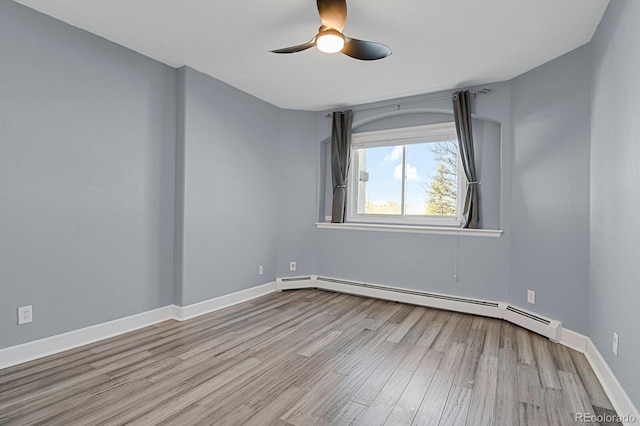 unfurnished room featuring baseboards, ceiling fan, baseboard heating, and wood finished floors