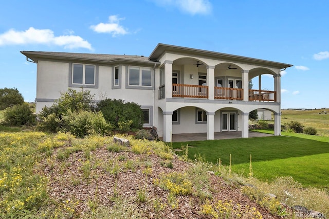 rear view of house featuring french doors, a patio, stucco siding, a lawn, and ceiling fan