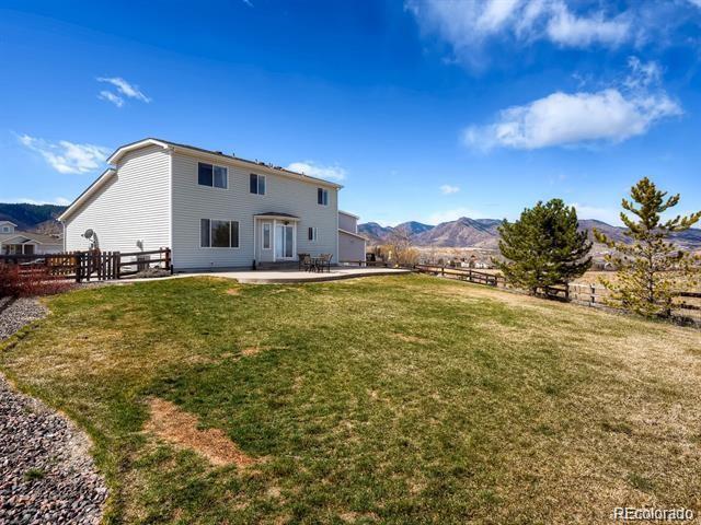 rear view of property with a mountain view, a patio, a lawn, and fence