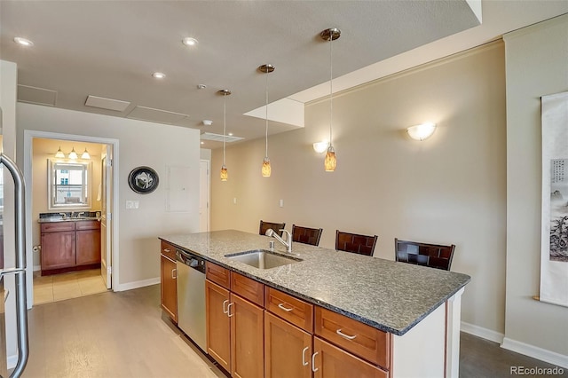 1975 Grant St Unit 501, Denver, CO 80203 - kitchen with dishwasher, dark stone counters, a kitchen island with sink, pendant lighting, and brown cabinets