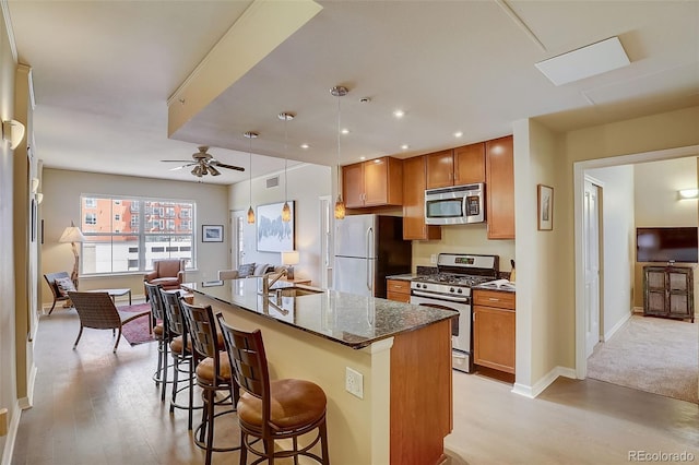 1975 Grant St Unit 501, Denver, CO 80203 - kitchen with stainless steel appliances, open floor plan, a kitchen bar, light wood-style flooring, and recessed lighting