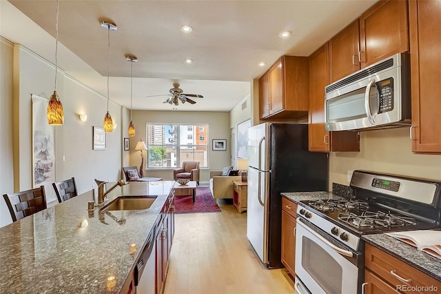 1975 Grant St Unit 501, Denver, CO 80203 - kitchen featuring appliances with stainless steel finishes, brown cabinets, light wood-style flooring, open floor plan, and recessed lighting