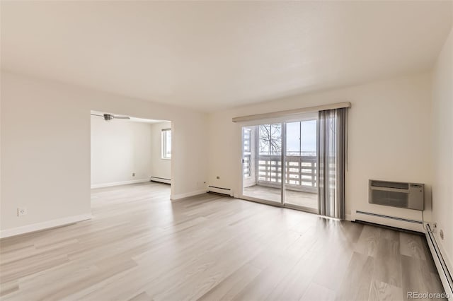 empty room with light wood-type flooring, a baseboard radiator, a baseboard heating unit, and a wall mounted air conditioner