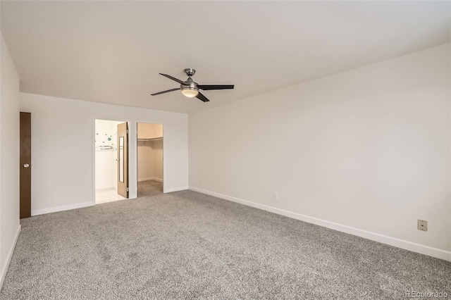 unfurnished bedroom featuring baseboards, ceiling fan, a walk in closet, and light colored carpet