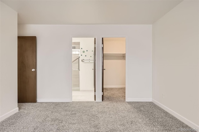 unfurnished bedroom with carpet floors, ensuite bath, a spacious closet, and baseboards