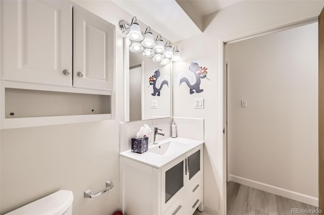 bathroom featuring toilet, baseboards, and vanity