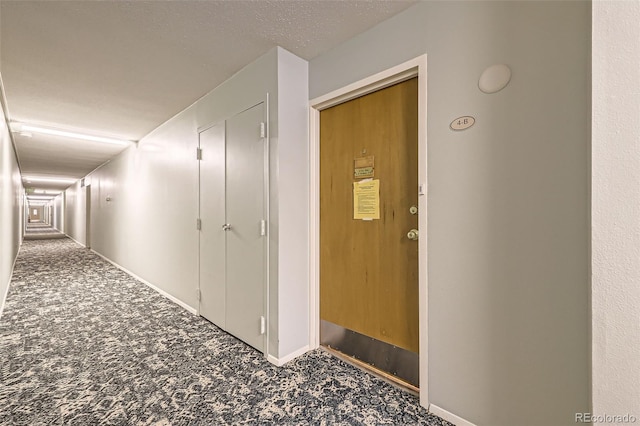 corridor with carpet and a textured ceiling