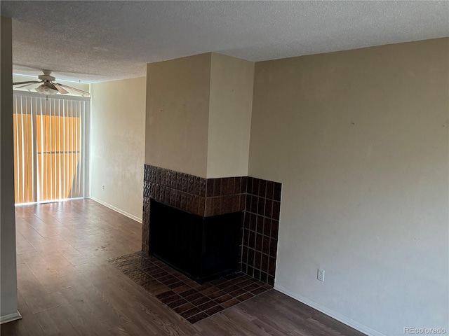 1967 S Oakland Way, Aurora, CO 80014 - empty room with dark wood-style flooring, a textured ceiling, a ceiling fan, baseboards, and a tiled fireplace