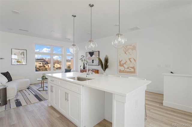 6971 E Lowry Blvd, Denver, CO 80230 - kitchen featuring a sink, light wood-style flooring, a kitchen island with sink, and light countertops