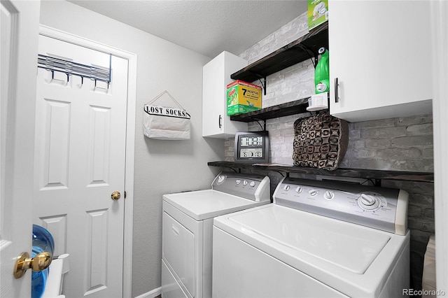 clothes washing area featuring a textured ceiling, washing machine and dryer, and cabinet space