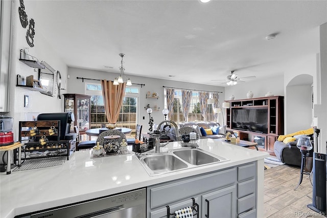 kitchen with arched walkways, a sink, open floor plan, dishwasher, and light wood finished floors