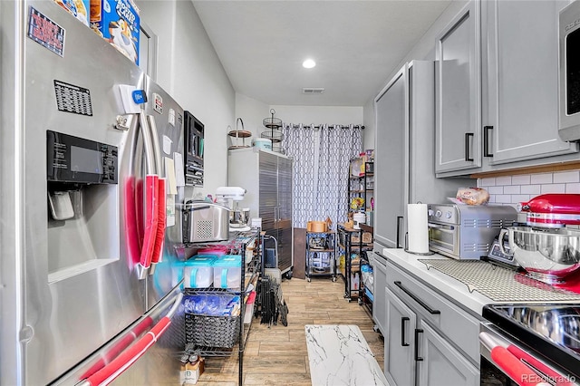 kitchen featuring visible vents, decorative backsplash, stainless steel appliances, light countertops, and light wood-type flooring