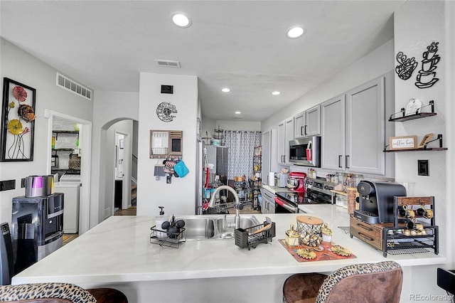 kitchen with stainless steel appliances, a peninsula, a sink, visible vents, and independent washer and dryer