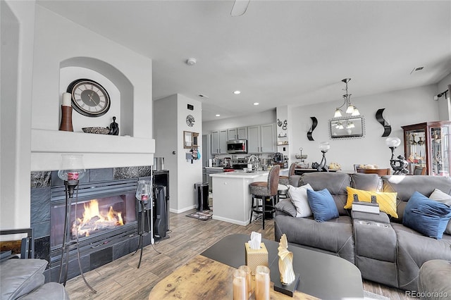 living area featuring recessed lighting, baseboards, wood finished floors, and a tile fireplace