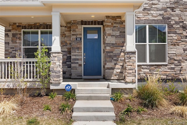 entrance to property featuring stone siding and a porch