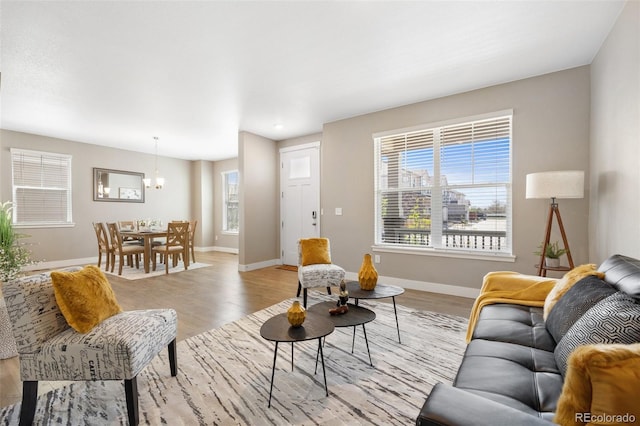 living room with baseboards, light wood-type flooring, and a chandelier