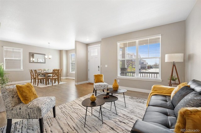 868 N Quatar St, Aurora, CO 80018 - living room with baseboards, light wood-type flooring, and a chandelier