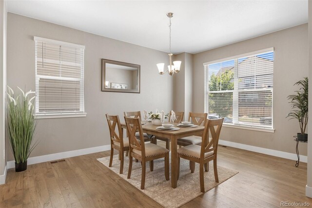 dining room featuring baseboards, a chandelier, and light wood finished floors