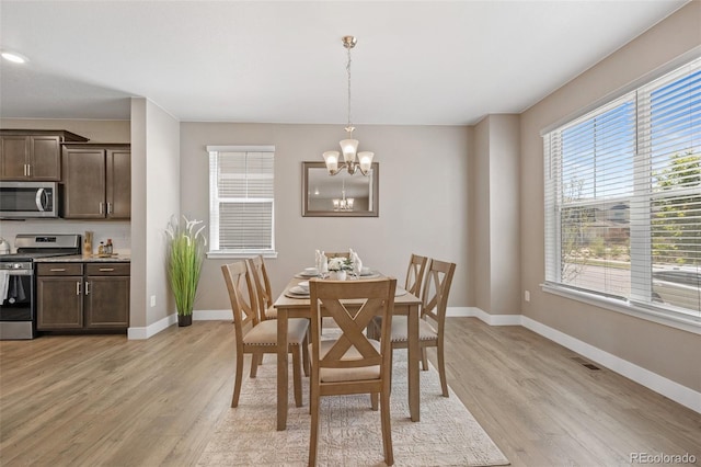 dining area with baseboards, a chandelier, and light wood finished floors