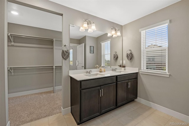 full bathroom with double vanity, a walk in closet, baseboards, and tile patterned floors