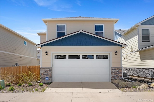 view of front of house featuring stone siding, concrete driveway, fence, and a garage