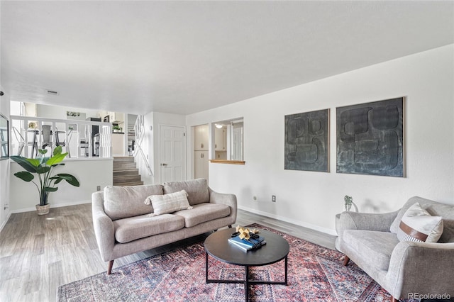 living room with wood finished floors, baseboards, and stairway