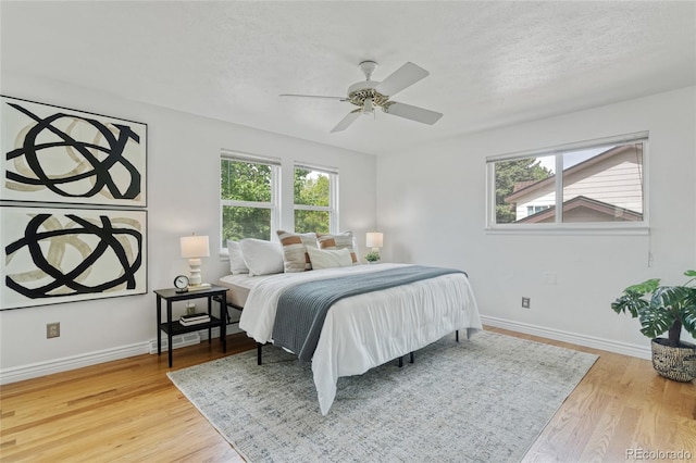 bedroom featuring wood finished floors, baseboards, a textured ceiling, and ceiling fan