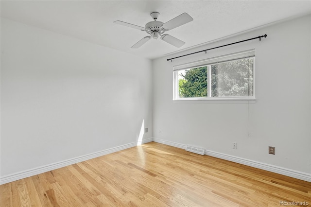 empty room with baseboards, wood finished floors, and a ceiling fan