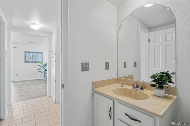 bathroom featuring tile patterned floors, vanity, and a textured wall