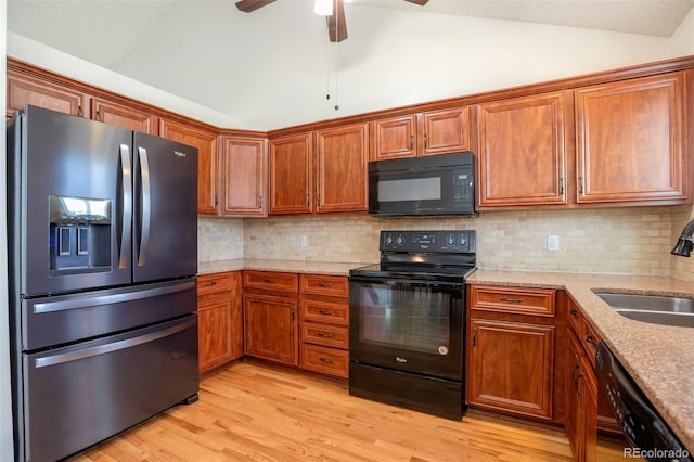 7732 Xavier Ct, Westminster, CO 80030 - kitchen featuring black appliances, vaulted ceiling, a sink, brown cabinetry, and light wood-style flooring