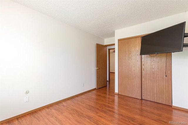 7732 Xavier Ct, Westminster, CO 80030 - unfurnished bedroom featuring wood finished floors, baseboards, a closet, and a textured ceiling
