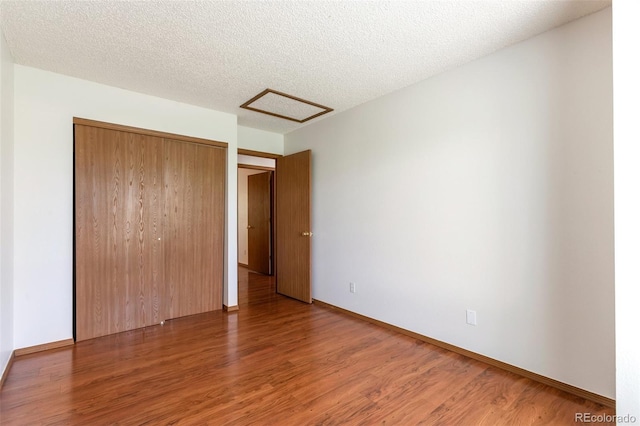 7732 Xavier Ct, Westminster, CO 80030 - unfurnished bedroom featuring attic access, wood finished floors, a closet, baseboards, and a textured ceiling