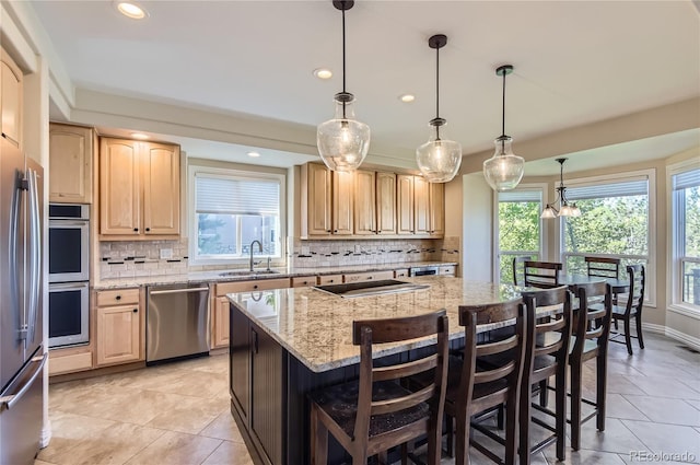 kitchen featuring stainless steel appliances, light brown cabinetry, a sink, a kitchen breakfast bar, and recessed lighting