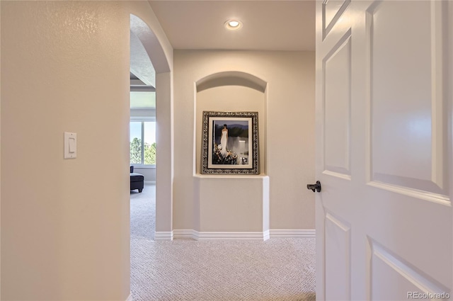 hall featuring carpet floors, arched walkways, baseboards, and recessed lighting