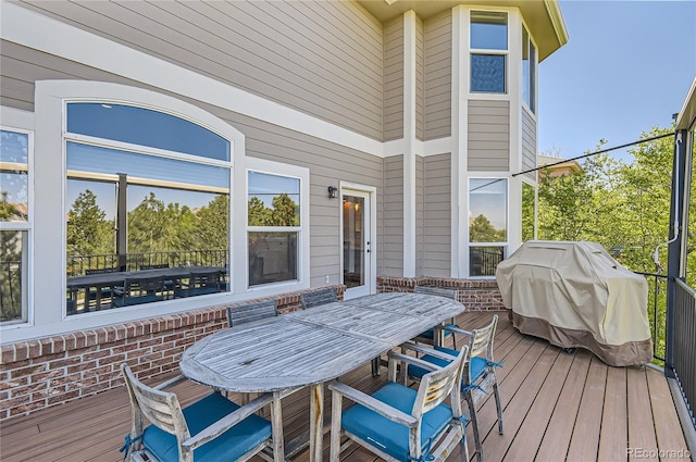 wooden terrace featuring outdoor dining space and a grill
