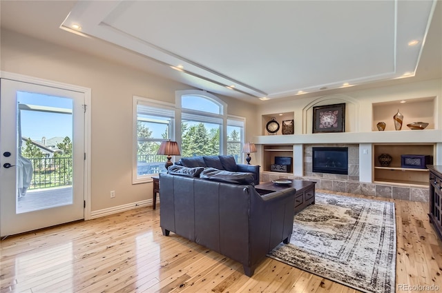 10529 Dacre Pl, Lone Tree, CO 80124 - living area with a tray ceiling, light wood-style flooring, a tile fireplace, and recessed lighting
