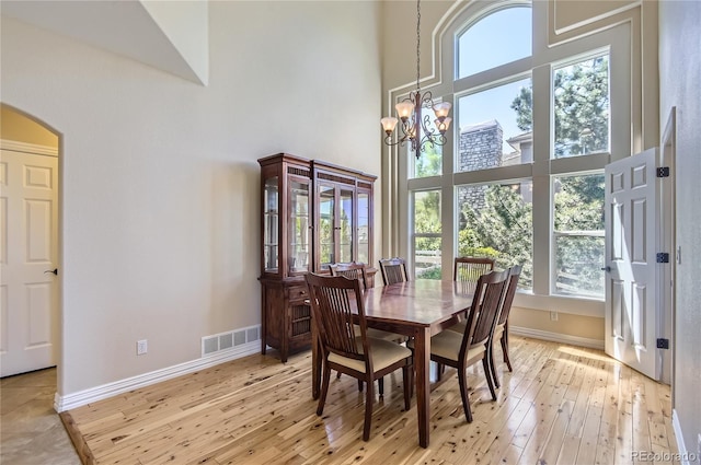 10529 Dacre Pl, Lone Tree, CO 80124 - dining space featuring a towering ceiling, arched walkways, light wood-style floors, and a chandelier