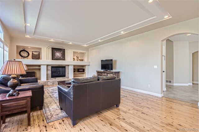 10529 Dacre Pl, Lone Tree, CO 80124 - living area with a tray ceiling, arched walkways, recessed lighting, light wood-style flooring, and built in features