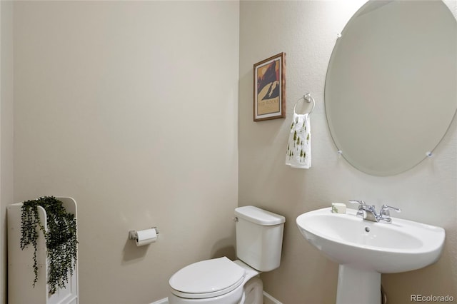 bathroom with baseboards, toilet, and a sink