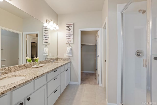 bathroom featuring tile patterned flooring, a stall shower, a spacious closet, and a sink