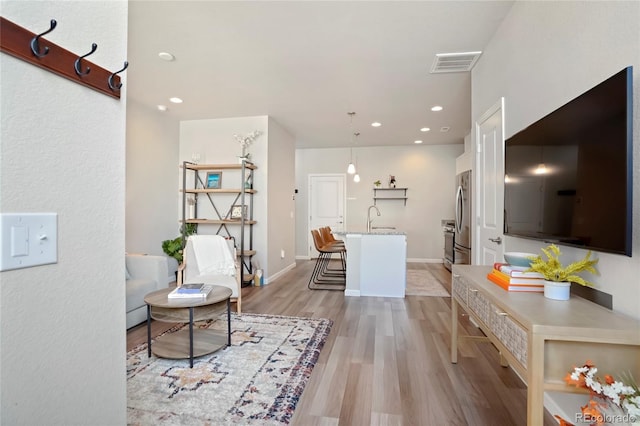 living room with baseboards, recessed lighting, light wood-style flooring, and visible vents