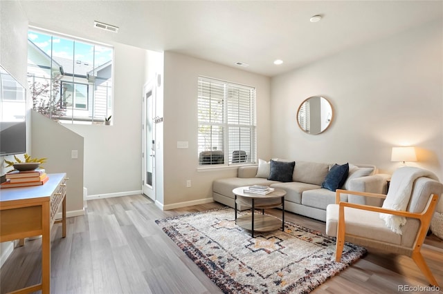 living room featuring light wood-type flooring, a wealth of natural light, baseboards, and visible vents