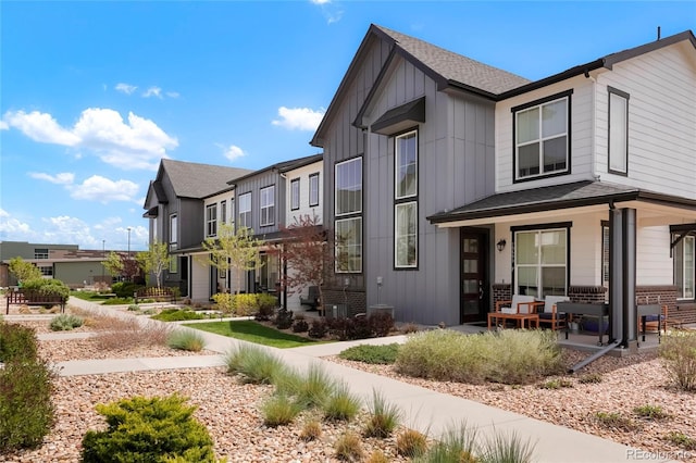 19593 W 93rd Ln Unit E, Arvada, CO 80007 - view of front of house featuring board and batten siding, a shingled roof, a porch, and brick siding