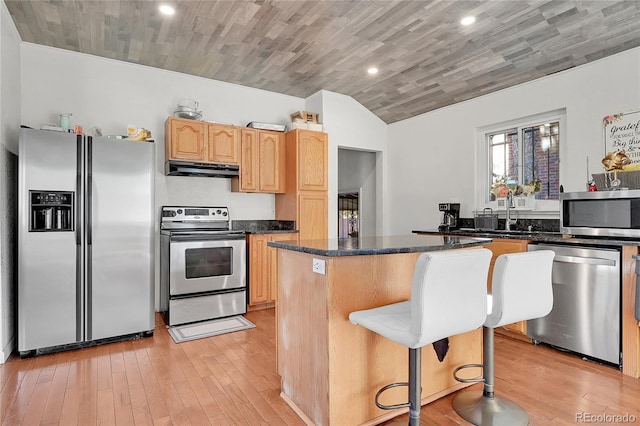 kitchen featuring stainless steel appliances, a center island, light hardwood / wood-style floors, and dark stone counters