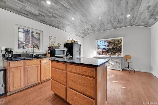 kitchen featuring sink, black refrigerator, a center island, light hardwood / wood-style floors, and vaulted ceiling