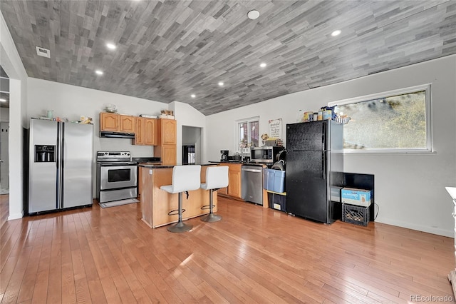 kitchen featuring a kitchen island, light brown cabinetry, a kitchen bar, light hardwood / wood-style floors, and stainless steel appliances