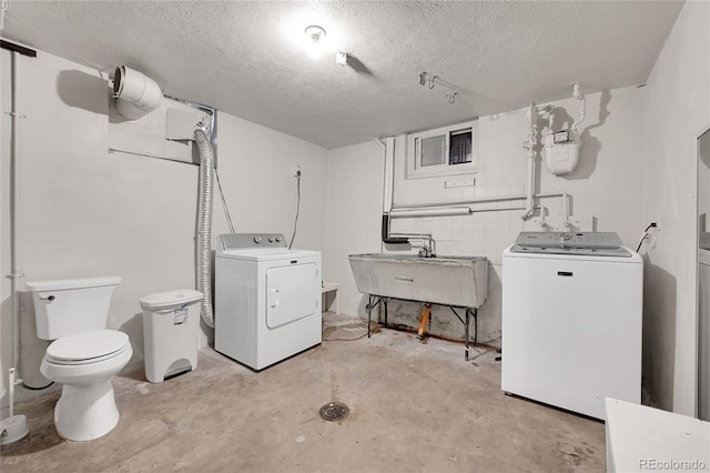 interior space featuring washer and clothes dryer, sink, concrete floors, and a textured ceiling