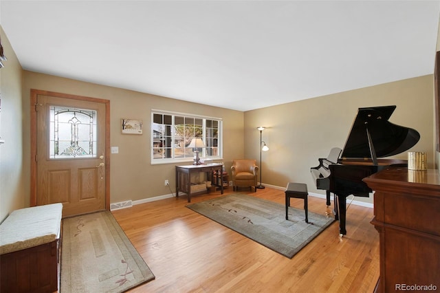 foyer entrance with light wood-style flooring, baseboards, visible vents, and a wealth of natural light