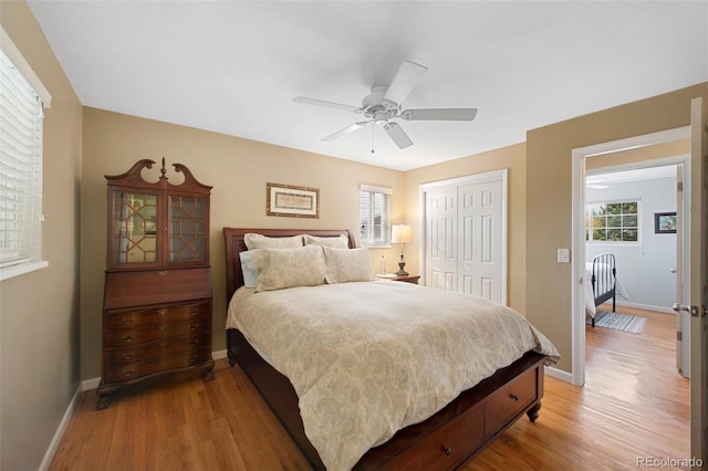 bedroom featuring a closet, multiple windows, light wood-type flooring, and baseboards